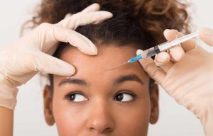 A young woman receiving a Botox injection—a minimally-invasive skin care procedure—in her forehead and between her brows.